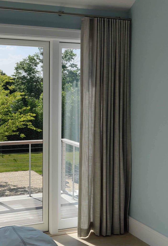 Curtains hanging by sunny glass door opening