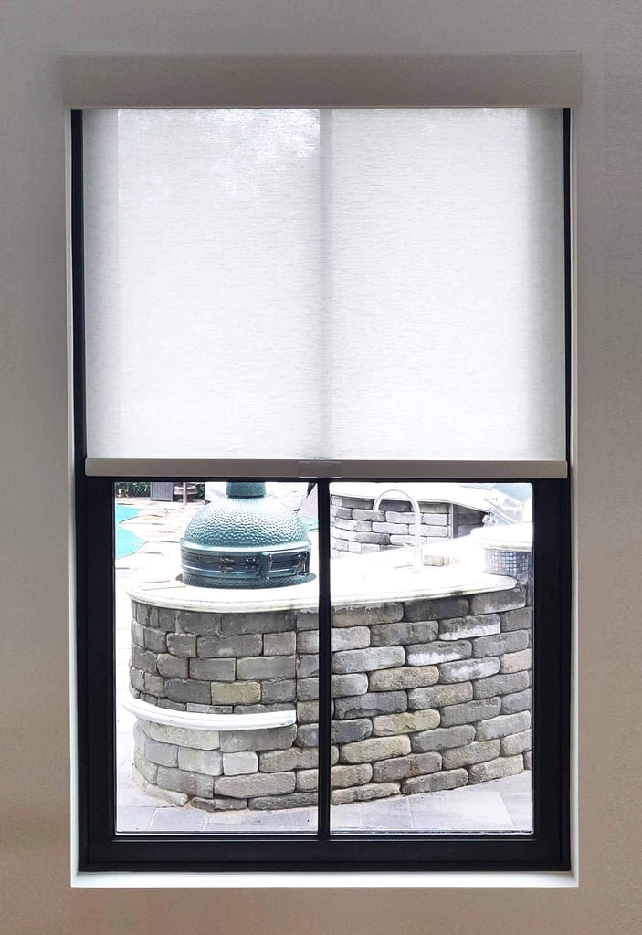 Window view of outdoor kitchen with grill