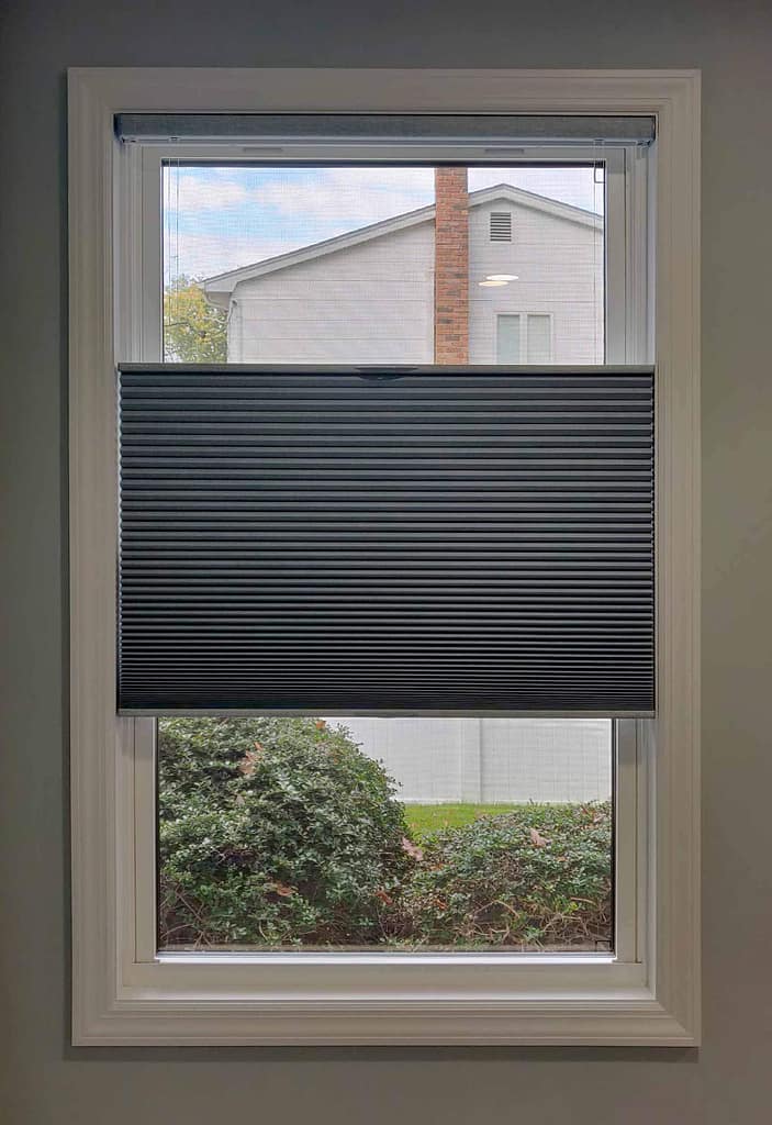 Window with half-open black pleated blind