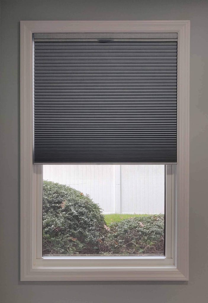 Gray window shade half open with garden view