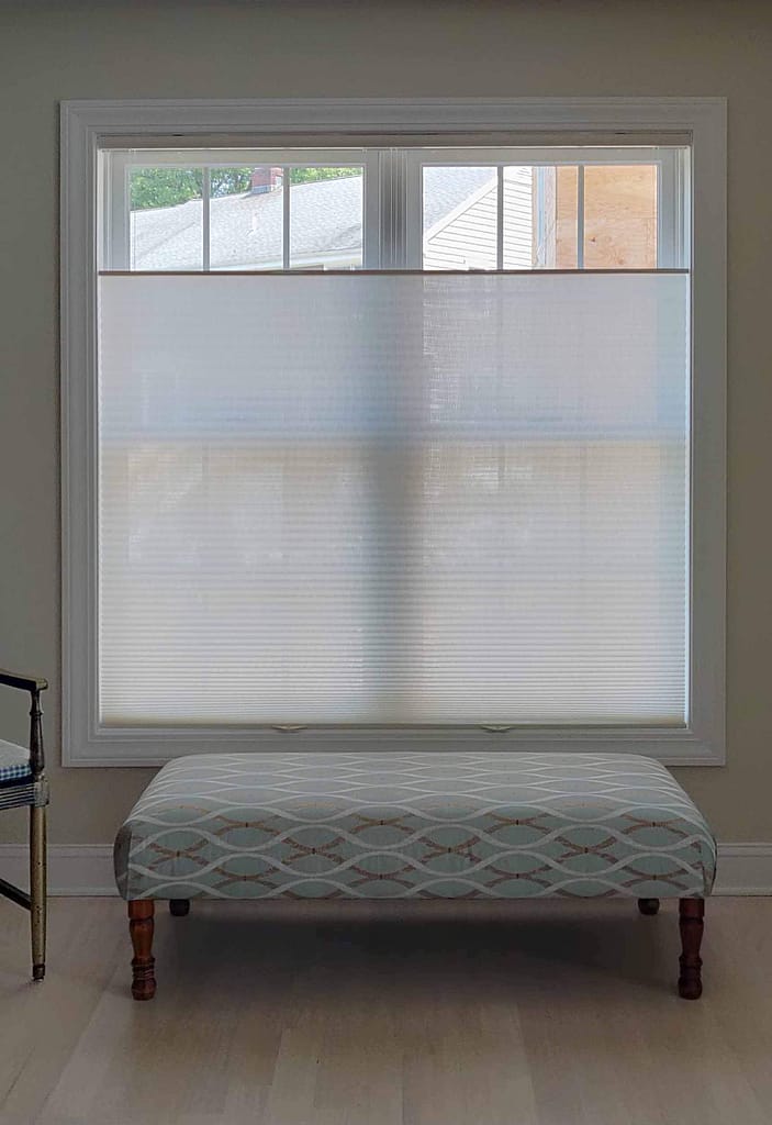 Window with sheer blinds and upholstered bench