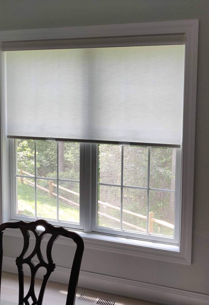 White roller blinds on sunny window frame.