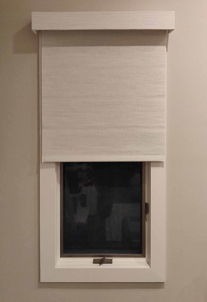 White roller blind covering a small window