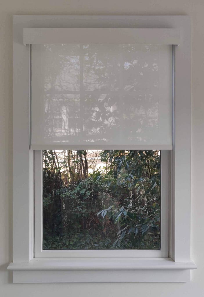 Window with partially lowered white roller blind